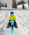 Child riding Steerable Ski Sled With Steering Wheel And Twin Brakes, Heavy Duty Go Kart Snow Scooter in winter with snow background.
