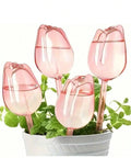 Pink Tulip Watering Globes For Indoor And Outdoor Plants Self Watering Bulbs That Slowly Release Water To Keep Pots Hydrated For 7 To 14 Days No Fuss Easy Care For Busy Plant Parents In A 2 Or 4 Pack in a white planter with green plants