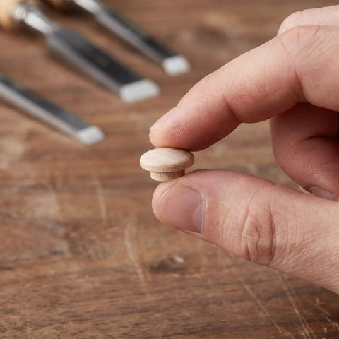 Hand holding mushroom head wood plug for screw holes unfinished button caps with easy press in installation