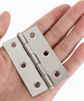 Close-up view of a stainless steel 3-inch door hinge held in hand, with six mounting holes and polished finish.
