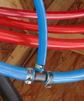 DIY Friendly PEX B Tubing Sticks 0.5 Inch By 4 Feet Red And Blue Potable Water And Hot Water Tubing For Indoor Outdoor Use Pre Cut Convenience Easy Install Replacement For Small Plumbing Jobs installed with metal clamps on wooden support.