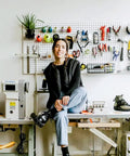 Person seated in front of a wall-mounted Double Pack Metal Pegboard Panels for Walls with tools in craft room.