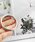 Person holding 10 Pcs Big Round Carabiner Clips, 2 Inch, 50 Mm, Metal Trigger Snap Hooks With O Rings For DIY Charms, Keychains, Bags