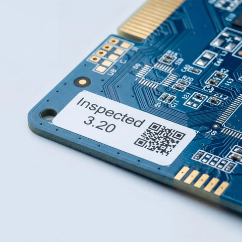 Close-up of printed circuit board with inspection label and QR code, showcasing electronic components.