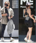Two women in activewear, one carrying a yoga mat and gray laundry bag, the other opening a door with a small purse, outdoors.