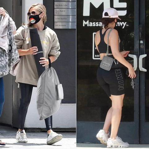Two women in activewear, one carrying a yoga mat and gray laundry bag, the other opening a door with a small purse, outdoors.