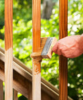 Hand using Dope 3 Inch Block Stain Brush For Deck And Fence Staining Thick Flat Paint Brush With Soft Bristle Blend on wooden railing