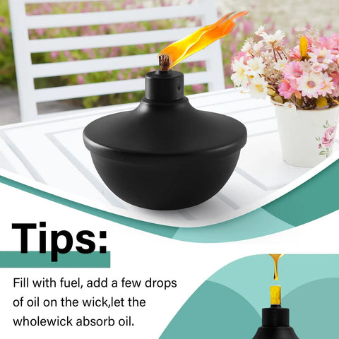 Close-up of a lit black metal table top torch on a white table, part of a Six Pack Metal Table Top Torches With 23.5 Oz Citronella Fuel For Outdoor Parties And Garden Decor Refillable Flame Torches With Wicks And Covers Long Lasting Burn Time Of Over 18 Hours set.