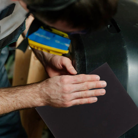 Person using Top Tier 9 Sheets Wet Dry Sanding Paper Assortment featuring 9 Grits for automotive surface finishing.