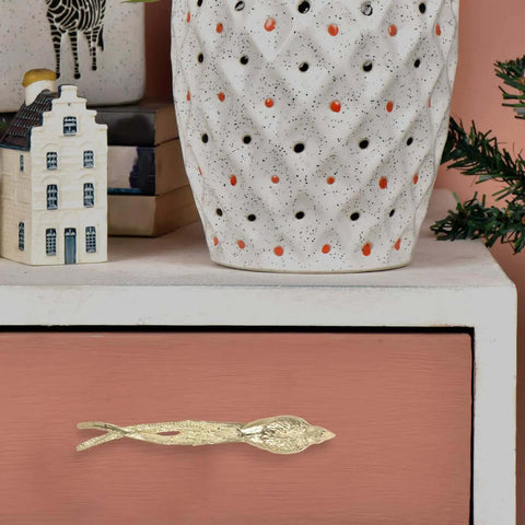 Dope Brass Bird Shape Cabinet Handles With Golden Finish on pink drawer, with white vase and decorative items on top