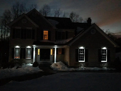 Six Pack Outdoor Solar Powered LED Gutter Lights illuminate house exterior at night, rain resistant, rechargeable AA battery included.