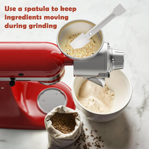 Red KitchenAid stand mixer with all-metal grain mill attachment on top, grinding oats into flour.