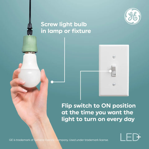 Hand holding Smart LED A19 Light Bulbs With Built In Timer Auto On Off Schedule next to light switch, E26 base