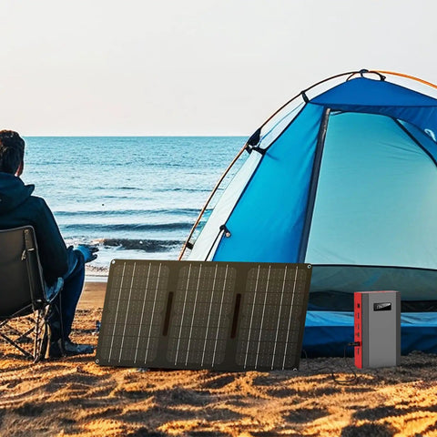 Grey red Portable Power Bank With AC Outlet 65W External Battery for RV camping next to tent and solar panel on beach