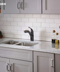 Brecklyn Mediterranean Bronze Single Handle Pull Out Sprayer Kitchen Faucet With Power Clean Tech installed on white tiled backsplash
