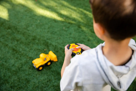 Child playing with Kid Friendly RC Loader Truck With Easy To Use Controller, 10.5 Inch Construction Vehicle on grass
