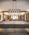 Issac 34 Inch Five Light Farmhouse Island Light In Smoked Birch Finish hanging above pool table in rustic modern room.
