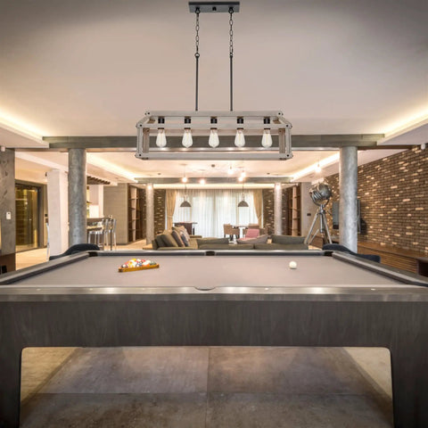 Issac 34 Inch Five Light Farmhouse Island Light In Smoked Birch Finish hanging above pool table in rustic modern room.