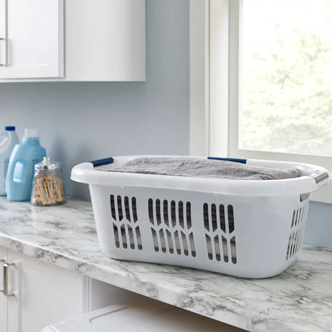 XL Hip Hugger Laundry Basket 2.1 Bushel White With Royal Blue Handles sitting on marble counter holding grey towel in laundry room
