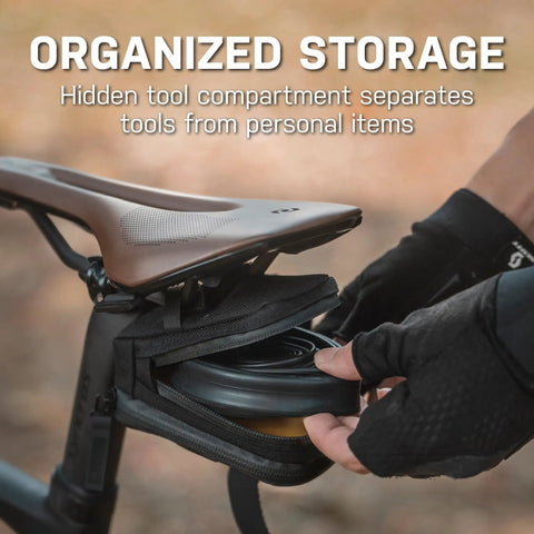 Cyclist accessing Elementa GearBag Under-Seat Bike Bag With Dual Compartments Quick Access Rail Wing System mounted on bike.