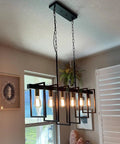 Farmhouse Dining Room Chandelier With Six Lights In Black Finish 39.4 Inch Hanging Kitchen Island Light Modern Metal Frame Adjustable Rods And Chain Rustic Yet Contemporary Ceiling Fixture For Bright Everyday Living displaying warm bulbs over a dining table.