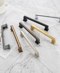 Assorted cabinet pulls on marble, including Stepped Bar Cabinet Pull in Oil Rubbed Bronze, 5 Inch Screw Spacing, 25 Pack.
