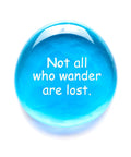 Blue glass stone with 'Not all who wander are lost,' part of Geocache Swag Glass Stones Set Of Six With Fun Images In A Deluxe Gift Box.