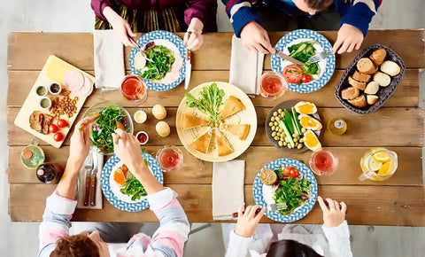 People dining with Heavy Duty 10 Inch Paper Plates Bulk Pack Thickened Disposable Dinner Plates For Holidays, Parties, Picnics And Everyday Use Sturdy Yet Lightweight Eco Friendly Renewable Materials 100 Count, with salads and drinks.