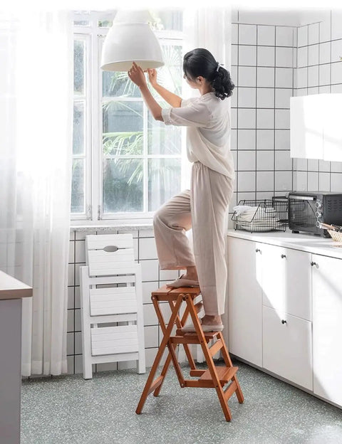Woman using 3 Step Wooden Folding Stool Chair With Solid Pine Frame Sturdy Portable Ladder For Home Library And Garden in kitchen