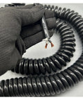 Rock Solid Retractable Coiled Power Cord with Copper Core held with black gloves, showing flexible 20m design, ideal for heavy duty tasks.
