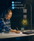 Woman writing beside Lit Magnetic Levitating Light Bulb Lamp With Black Base, featuring anti-drop and energy-saving features.