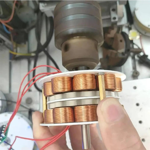 Close-up of dual-layer iron core hydro generator with visible copper coils and wiring inside a workshop setting.