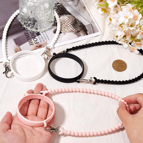 3 Pack Water Bottle Handle Straps Set in Pink White Black, Soft Silicone Sling Carriers for Walking and Hiking displayed on table