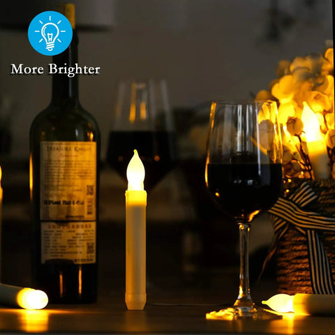 12 Pack Battery Operated Taper Candles With Remote, Warm White Flicker, Flameless LED Handheld on table with wine bottle.