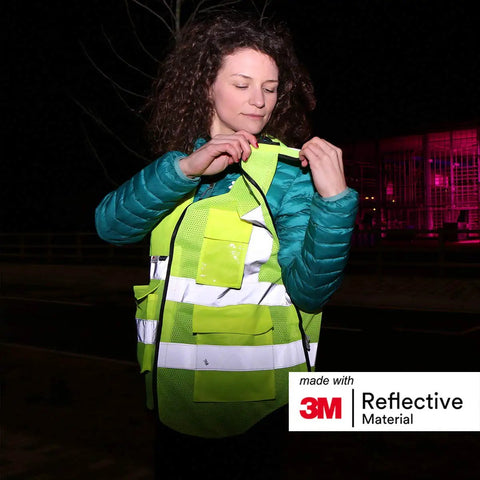 Heavy Duty Breakaway Mesh Hi Vis Safety Vest With 3M Reflective Strips modeled by a woman adjusting it at night.