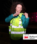 Woman adjusting Road Warrior Breakaway Mesh High Vis Safety Vest With Premium 3M Reflective Strips For Maximum Nighttime Visibility Ansi 107 Certified Job Site Armor Daily Grind Gear at night.