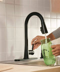 Person using the Precept Pull-Down Kitchen Faucet, 1.5 GPM, Matte Black Finish, Powerinse 3-Function Sprayer for Extra Cleaning.