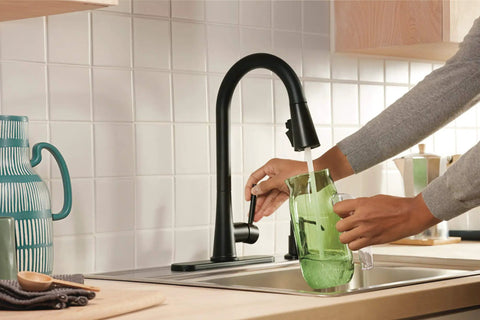 Person using the Precept Pull-Down Kitchen Faucet, 1.5 GPM, Matte Black Finish, Powerinse 3-Function Sprayer for Extra Cleaning.