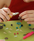 Person using pliers with Colorful Mix Screw Eye Pins Kit Handy For Jewelry Making And DIY Crafts on a green table.