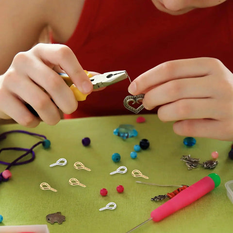 Person using pliers with Colorful Mix Screw Eye Pins Kit Handy For Jewelry Making And DIY Crafts on a green table.