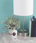 1080P HD Wi-Fi Security Cam with Wide Angle View next to lamp and plant on marble table, for home or office use