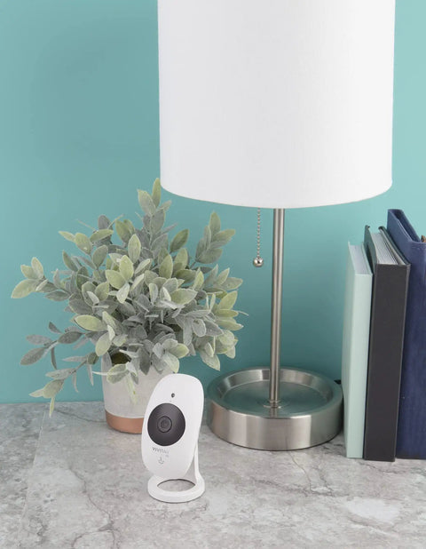 1080P HD Wi-Fi Security Cam with Wide Angle View next to lamp and plant on marble table, for home or office use