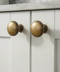 Classic Round Antique Brass Cabinet Knobs Set Of 6 With 1 1/4 Inch Head Diameter Vintage Aged furniture hardware on white cabinets.