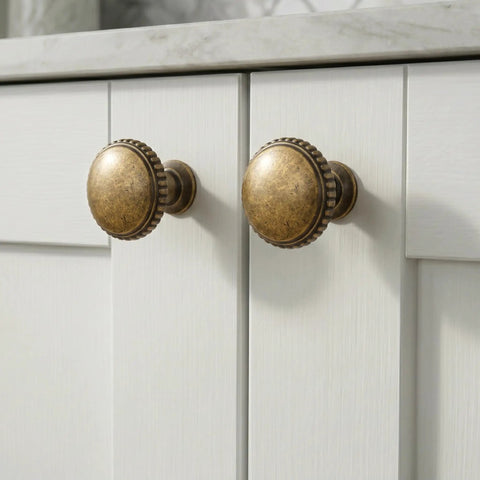 Classic Round Antique Brass Cabinet Knobs Set Of 6 With 1 1/4 Inch Head Diameter Vintage Aged furniture hardware on white cabinets.