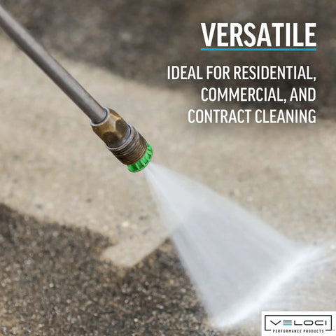 Close-up of a pressure washer nozzle tip with a green ring on a metal wand spraying water on concrete.