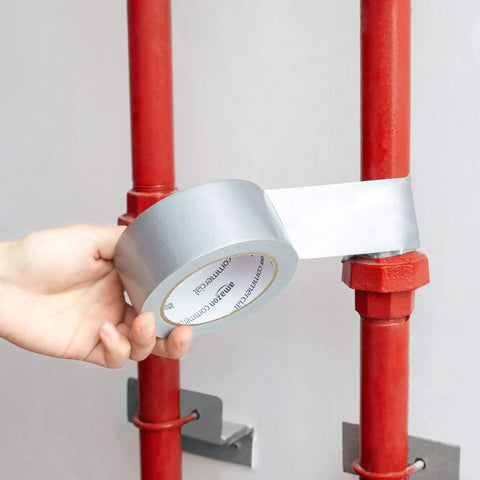Hand applying Standard Duct Tape 1.88 Inch By 30 Yard Silver 12 Pack For Quick Repairs Patching Bundling And Packaging on red pipes