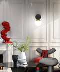 Black and Gold Globe Wall Sconce Mid Century Modern One Light Fixture in stylish living room with decorative elements.