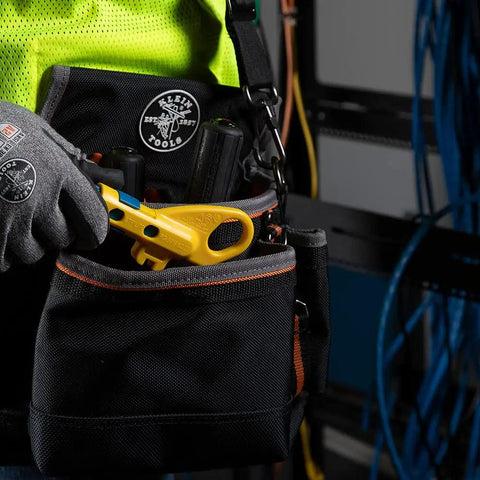 Technician holding a Data And Coax Cable Stripping Tool With Radial Design for RG59 RG6 and CAT3 to CAT6A in a tool belt pocket.