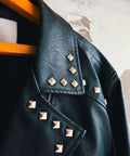 Silver pyramid stud accents on black leather jacket, front view along collar and shoulder