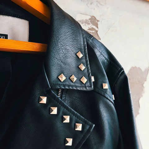 Silver pyramid stud accents on black leather jacket, front view along collar and shoulder